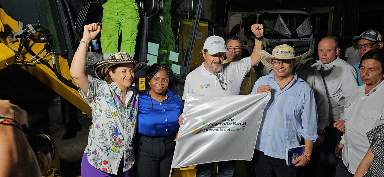 En la imagen se puede apreciar un grupo de personas, entre ellos, el presidente Gustavo Petro y la ministra Jhenifer Mojica, tambien se pueden apreciar dos personas más, uno de ellos, porta una bandera y es apoyado por el presidente y todos los presentes.