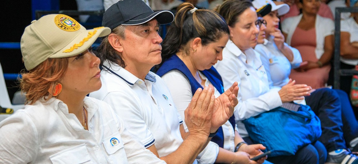En la imagen se ve a un grupo de personas sentadas en lo que parece ser un auditorio. Llevan camisas blancas a juego, lo que sugiere que podrían formar parte de un equipo u organización. Algunos aplauden, lo que podría indicar que están aplaudiendo una actuación, presentación o evento.