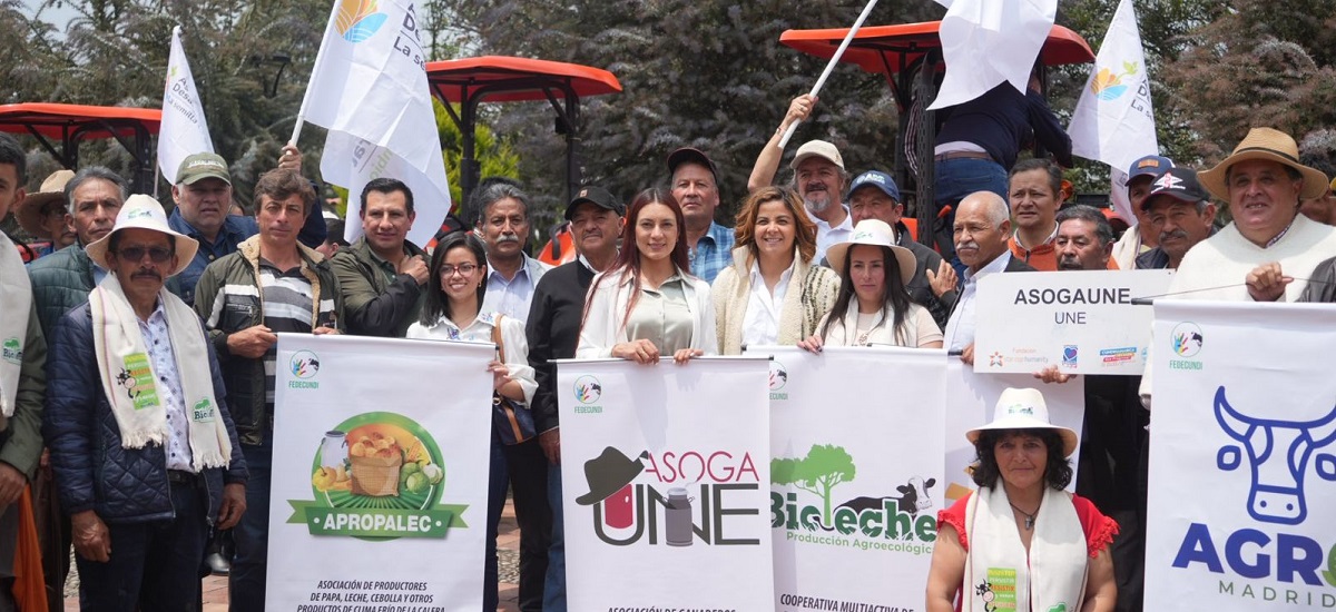 Esta imagen muestra a un grupo de personas reunidas. Llevan carteles y pancartas con diversos mensajes y logotipos, puede estar relacionado con cuestiones agrícolas.
