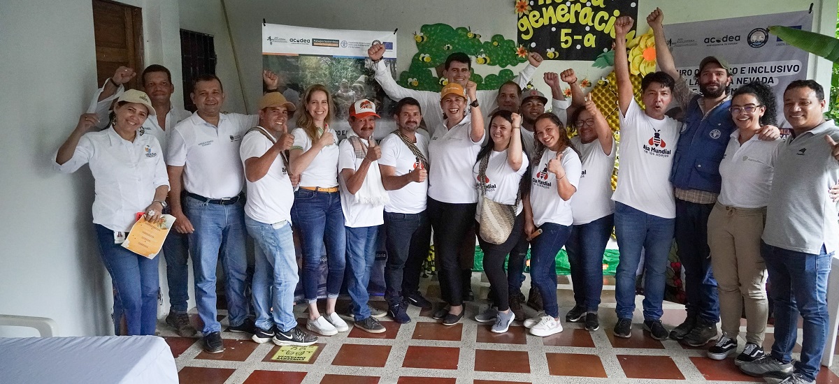 En la imagen se ve a un grupo de personas posando para una foto. Llevan camisetas blancas a juego, lo que sugiere que podrían formar parte de un equipo, organización o evento. Algunos de ellos levantan el puño, lo que podría indicar un gesto de unidad, fuerza o una causa específica que están apoyando.