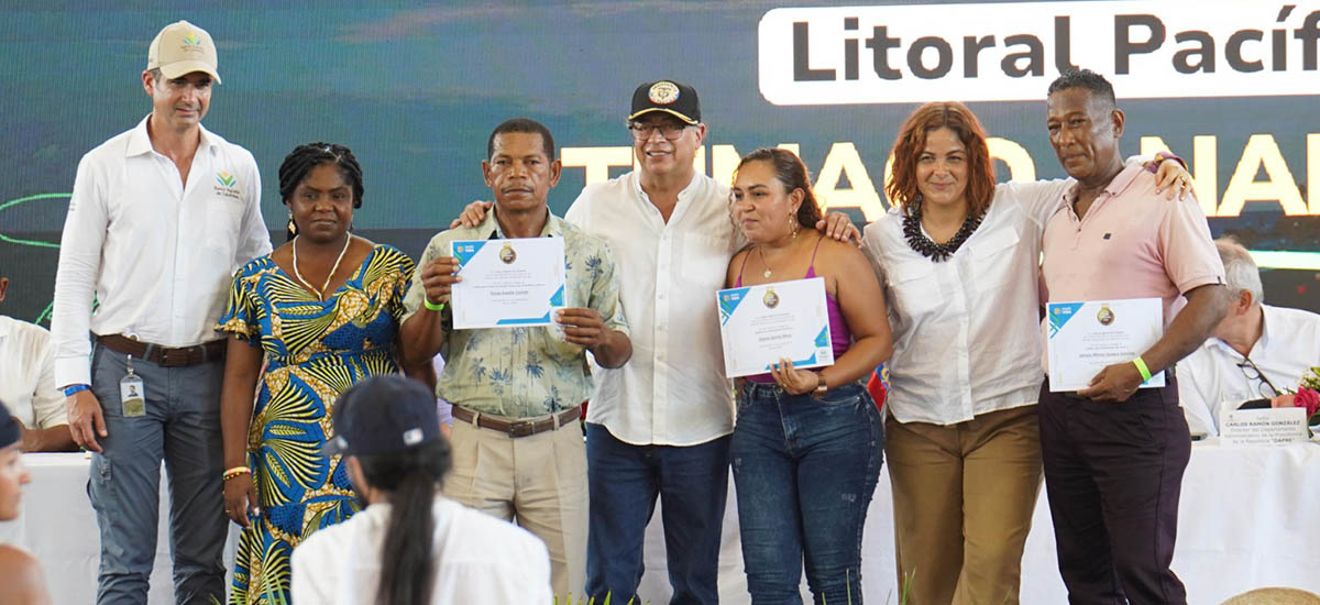En la imagen aparecen siete personas juntas, probablemente en un acto o ceremonia. Todos visten un atuendo semiformal y cada uno lleva en la mano un certificado o premio. Los certificados tienen un diseño similar, lo que sugiere que forman parte del mismo evento o reconocimiento.
