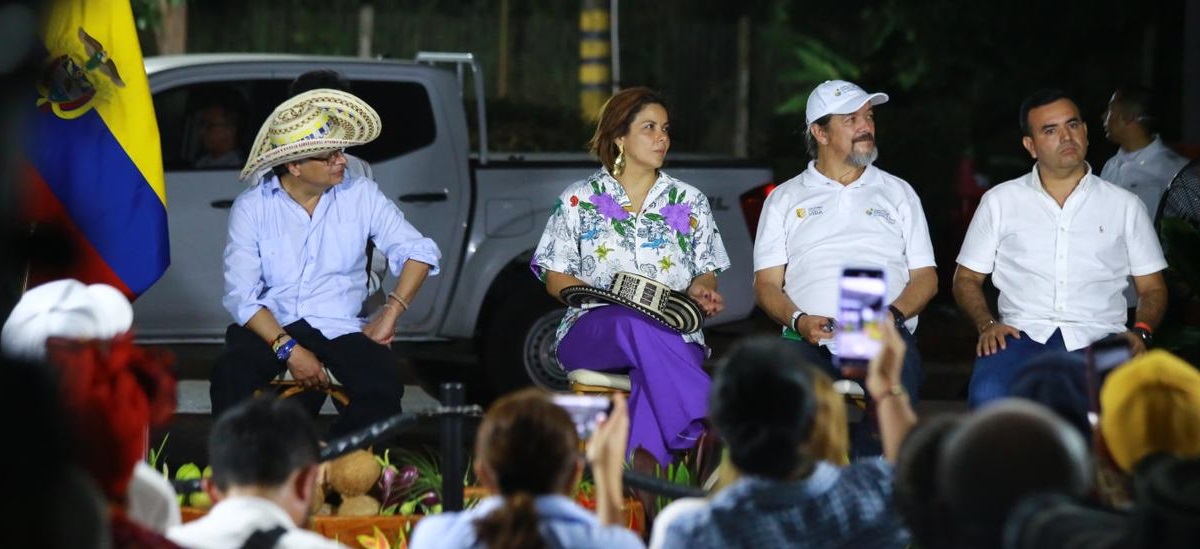 En la imagen aparecen cuatro personas sentadas en lo que parece ser un entorno público, posiblemente en un acto o reunión.