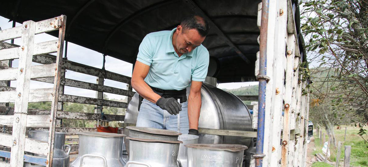en la imagen se puede apreciar a un hombre revolviendo con una cuchara lo que parece ser una vasija con algún producto lácteo