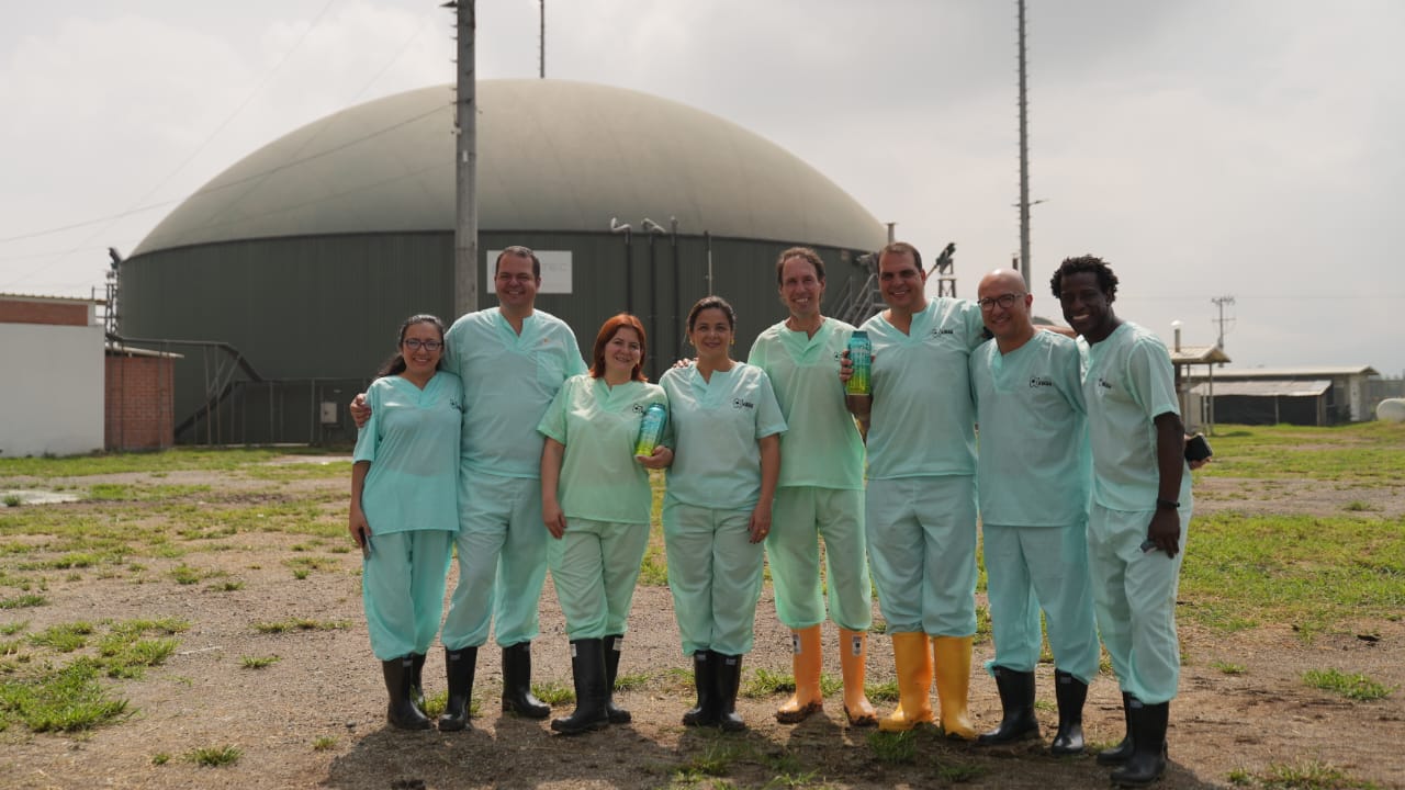En la imagen se puede observar a la Ministra Jhenifer Mojica, junto con un grupo de personas, todos vestidos igual, con trajes y botas, se ve que la ministra y uno de los señores sostienen un contenedor