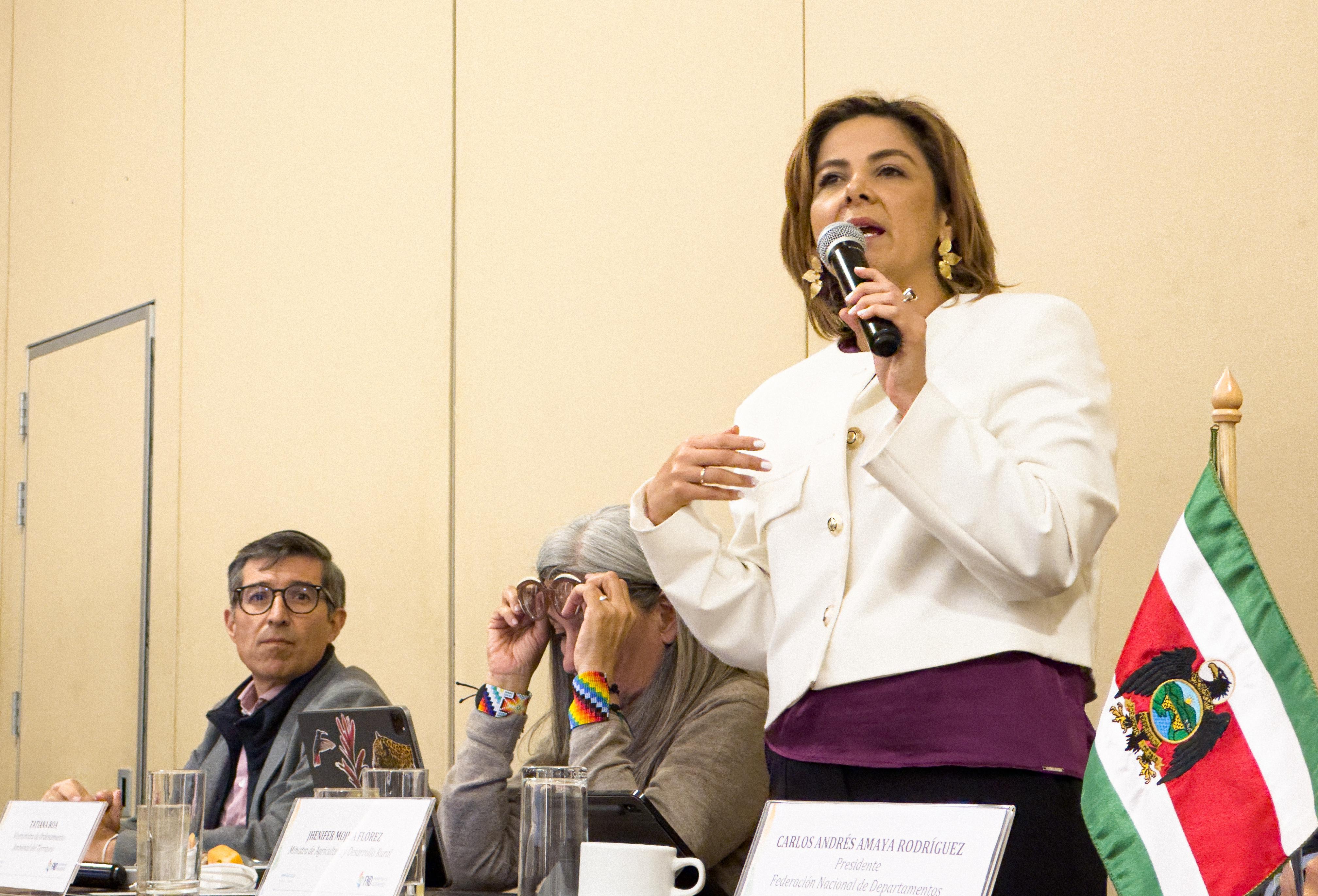En la imagen se puede ver a la ministra Jhenifer Mojica, la cual se encuentra hablando por un microfono, en lo que parece una reunion, El respaldo a la producción, transformación productiva sostenible y fortalecimiento a la asociatividad son las tres grandes apuestas del programa ‘Confianza Colombia’, y que tiene como prioridad que no se frene la senda económica por la que ha transitado la economía del sector agropecuario.   El viceministro (e) de Asuntos Agropecuarios, Germán Guerrero, precisó que desde el Gobierno del Cambio “se han movilizado recursos para inyectarle en el corto plazo al proceso de respaldo a la producción agropecuaria. Algunos de estos recursos se destinarán para compra de semillas, insumos y fertilizantes, asistencia técnica y manejo de suelos, entre otros”.   Sobre el tema de la transformación, el viceministro Guerrero resaltó que es momento de un apalancamiento hacia la agroindustria sostenible, y concluyó que se le dará prioridad a las comunidades que estén asociadas, por lo que invitó a gobernaciones y alcaldías a impulsar la asociatividad en el territorio. de ella están algunas personas poniendo mucho cuidado.