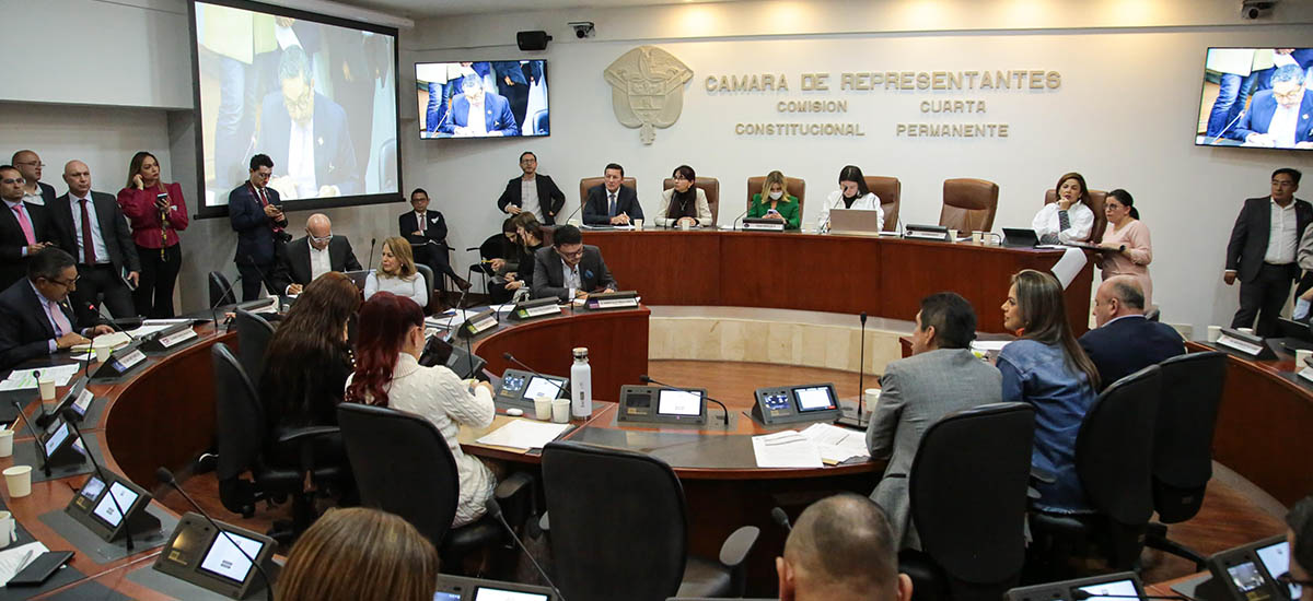 Esta imagen muestra a un grupo de personas en un entorno formal, probablemente una asamblea legislativa o parlamentaria. Están sentados alrededor de una gran mesa circular, típica de este tipo de órganos para facilitar la discusión y el debate. Las personas están vestidas con traje de negocios, lo que sugiere un entorno profesional.