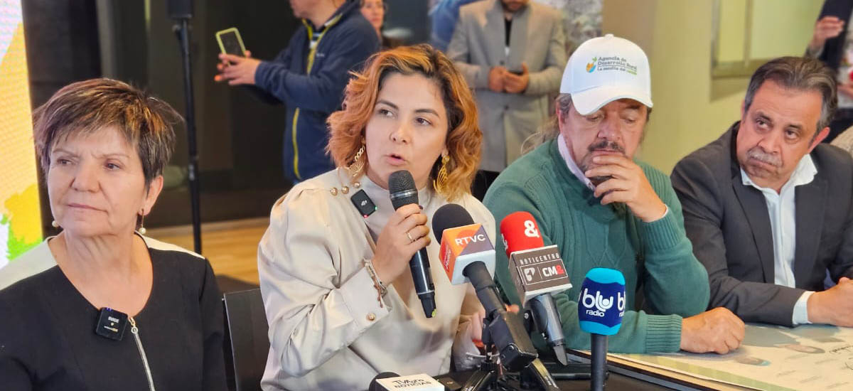 La imagen muestra un gran estanque de agua, circular y con un marco verde, que parece ser un estanque o un abrevadero. El estanque está rodeado por una valla, posiblemente para impedir la entrada de animales o personas. En la escena hay varios pájaros, algunos posados en la valla y otros volando por la zona. Los pájaros parecen disfrutar del agua y del entorno, lo que añade un ambiente animado a la escena.