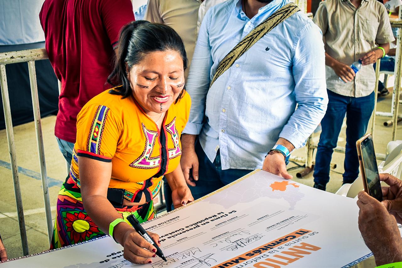 En la imagen se aprecia mujer firmando documentos 